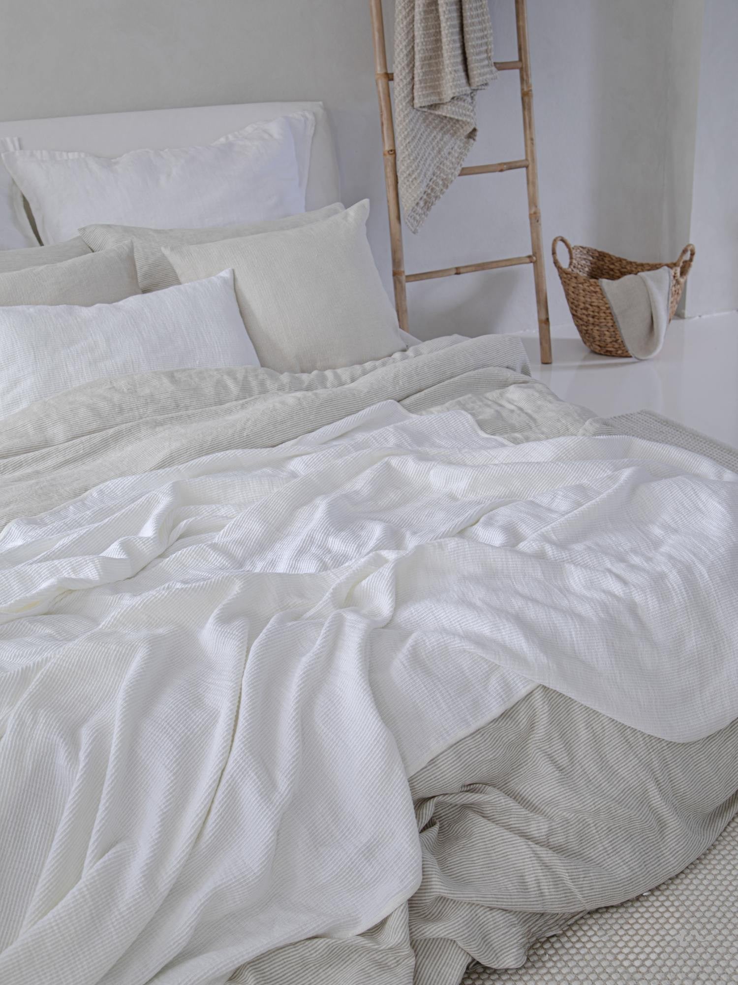 Locker fallende Leinen Bettwaesche Beige Weiss auf Bett, natuerlicher Look