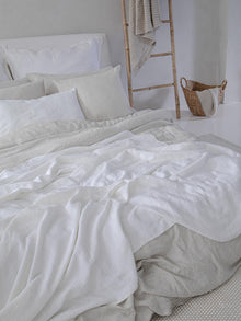 Locker fallende Leinen Bettwaesche Beige Weiss auf Bett, natuerlicher Look