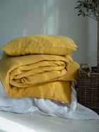 Leinen Bettwaesche Set Sonnengelb, gestapelte Kissen und Decken