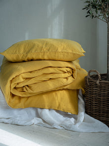 Leinen Bettwaesche Set Sonnengelb, gestapelte Kissen und Decken