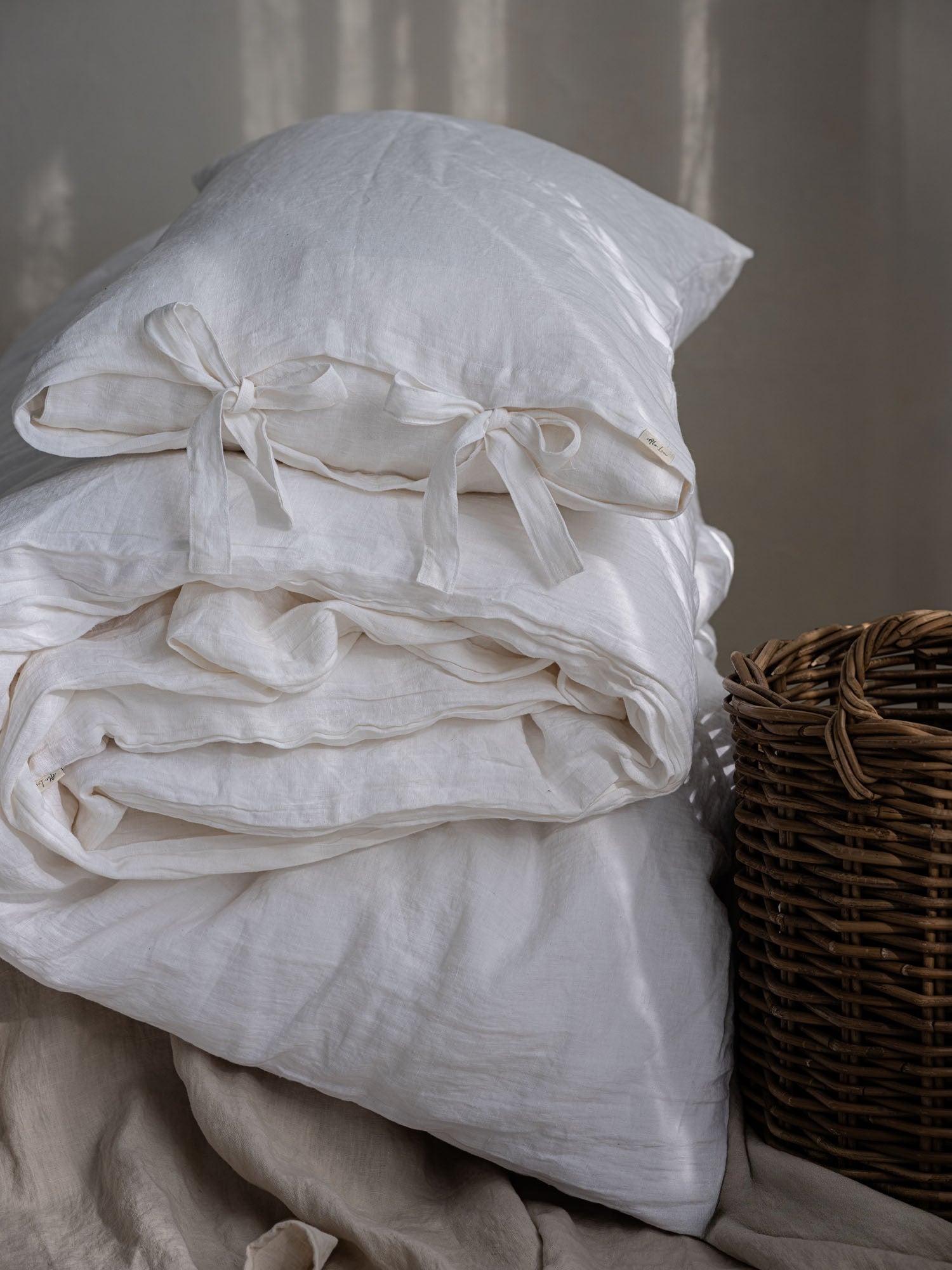 Leinen Bettwaesche Set in Jasminweiss, gestapelte Kissen und Decken