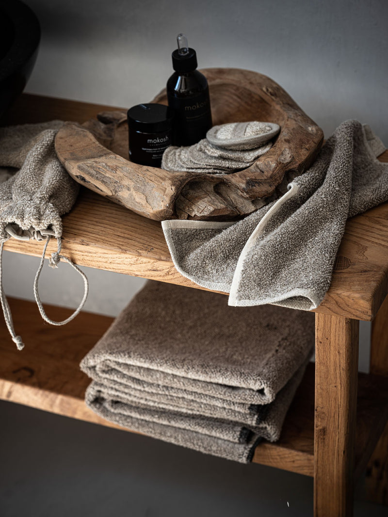 Pflegeset aus Leinen, Set aus Beutel, Handtuch und Pads auf Holztisch