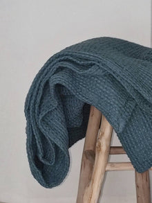 Rauchblaue Waffel Tagesdecke, zusammengerollt auf Bank