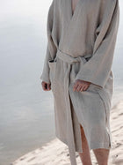 Zwei Personen im Waffel Bademantel Natur, am Strand sitzendZwei Personen im Waffel Bademantel Natur, am Strand sitzend