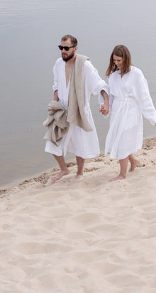 Paar mit Leinen Handtuechern am Strand, natuerlicher Look